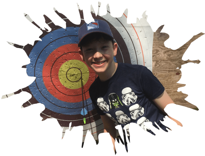 A young boy smiling next to a bullseye
